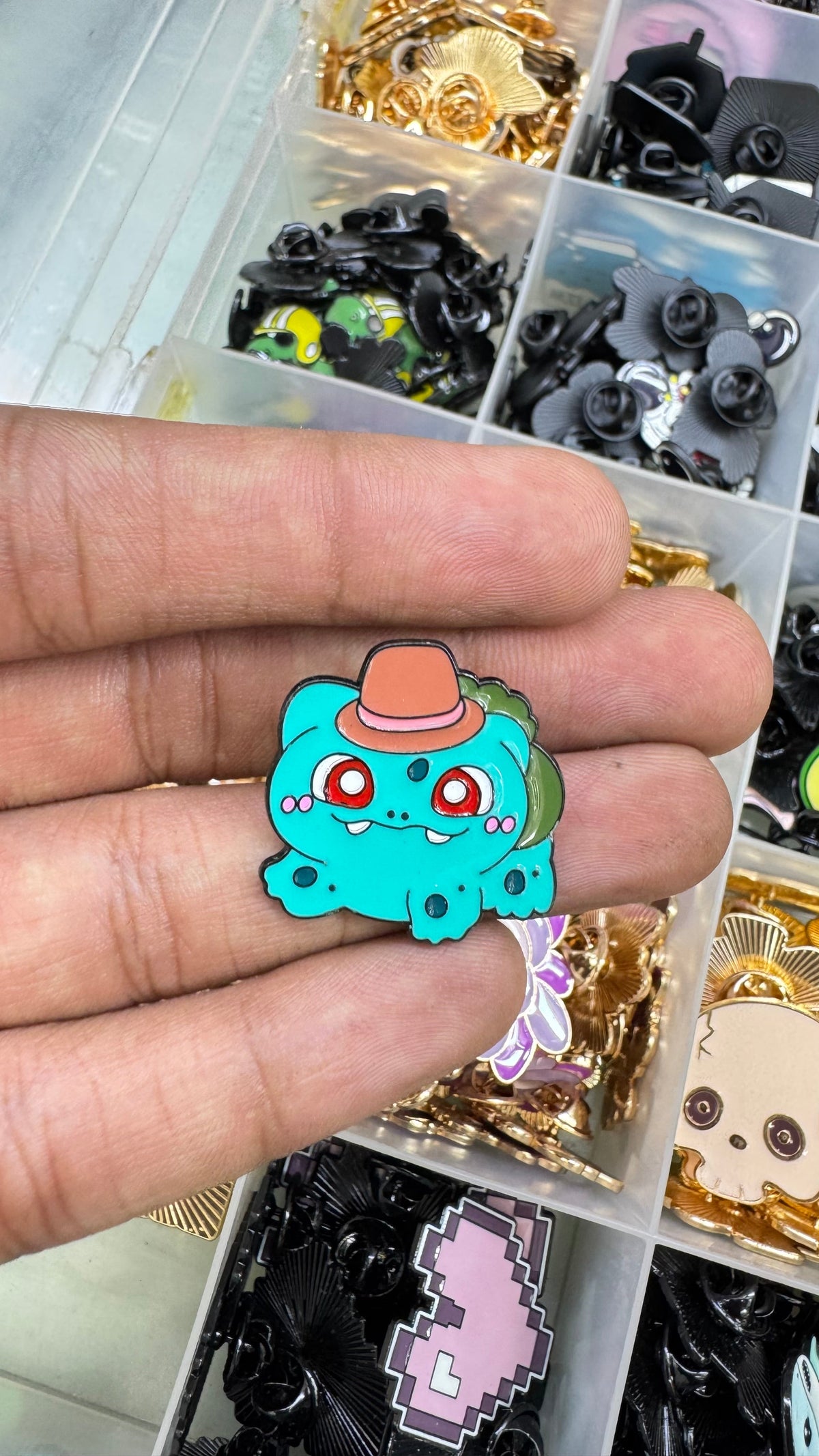 Century Fancy Beads enamel lapel pin featuring a teal Bulbasaur character wearing a small orange hat